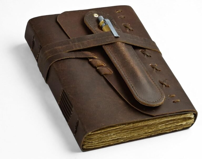 Brown leather journal with pen holder and strap closure on white background
